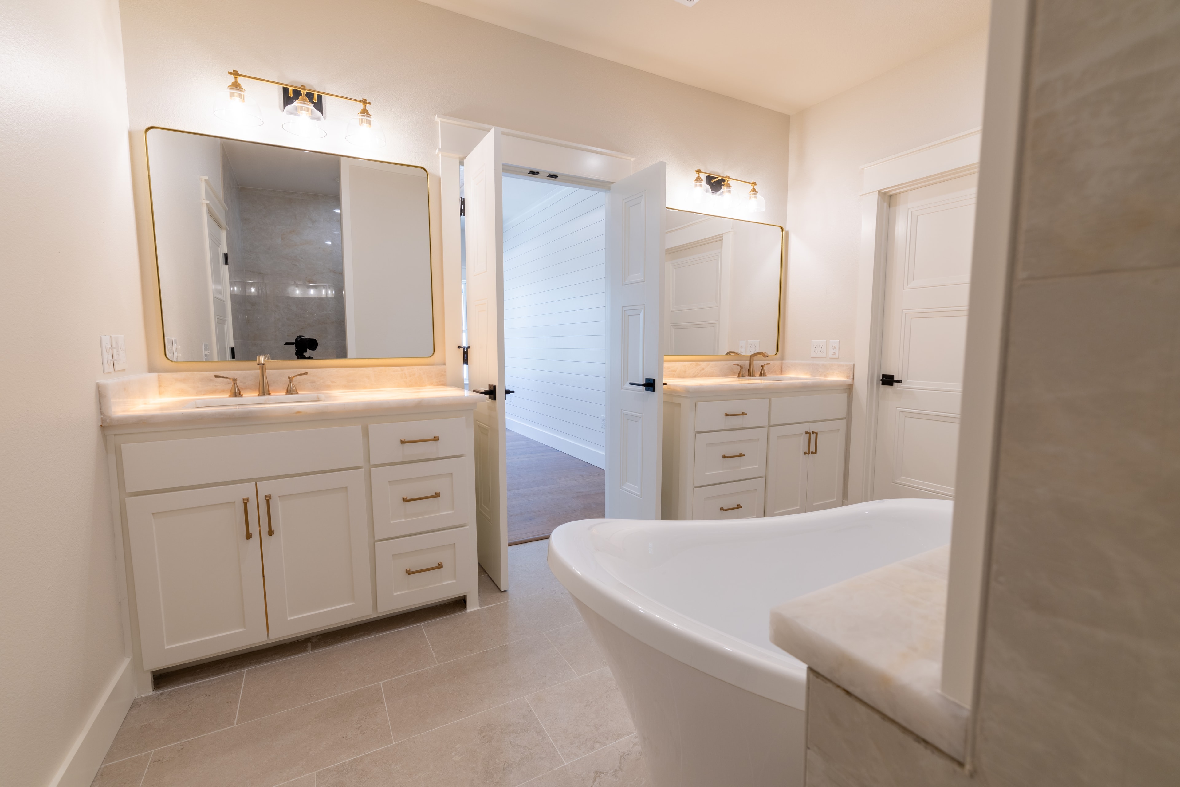 Master bathroom with dual vanities, gold fixtures, and freestanding tub